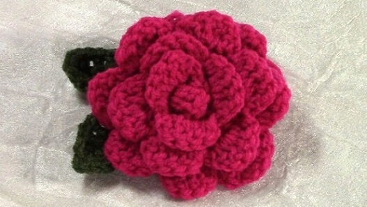 Pink crochet flower with dark green leaf