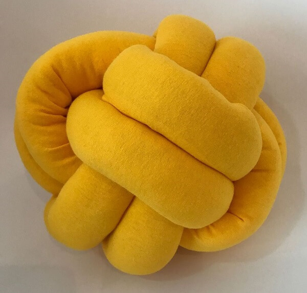 Knot-type cushion in yellow color brings joy to the decor