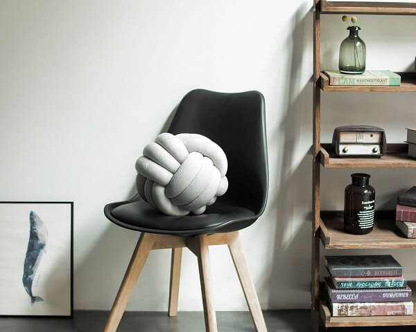 The white knot cushion stands out on the black chair