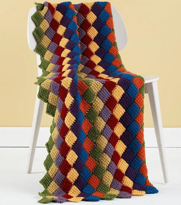 The colorful blanket made in Tunisian crochet brings relaxation to the space