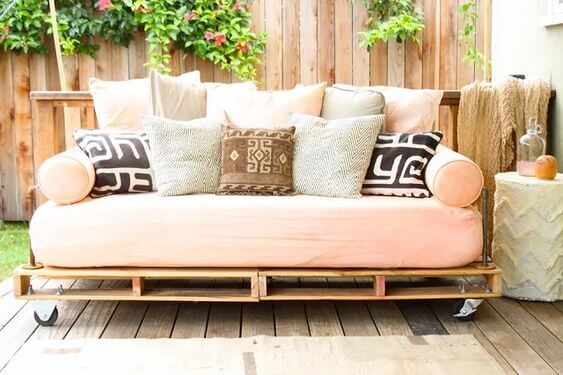 Sofá de palete rosa com almofadas confortáveis