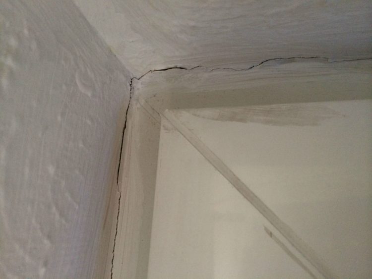 hairline cracks where wall meets ceiling